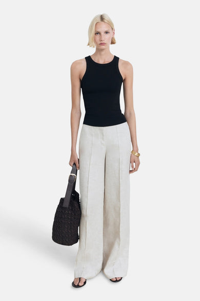 Zwarte singlet van MANGO, gedragen met crèmekleurige, wijde linnen broek, zwarte tas en gouden armband.
