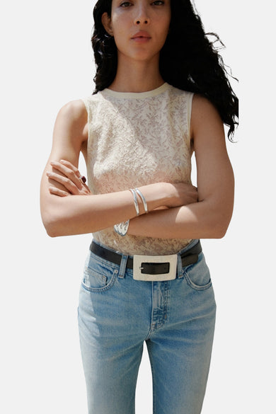 Ecru top zonder mouwen van MANGO, met een fijn, subtiel bladmotief en gecombineerd met jeans en zilveren armbanden.
