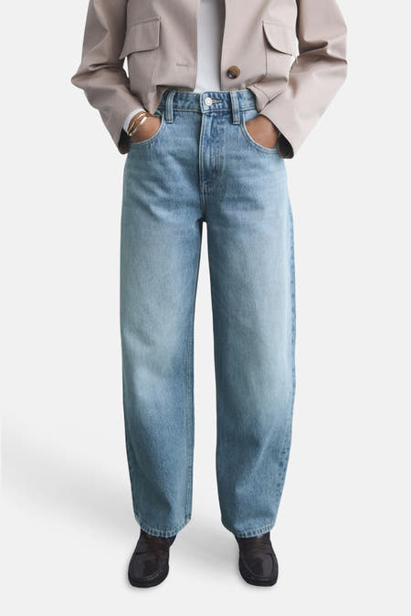 Jean en denim bleu clair de MANGO, avec des jambes larges et des poches à rabat, associé à une veste beige.