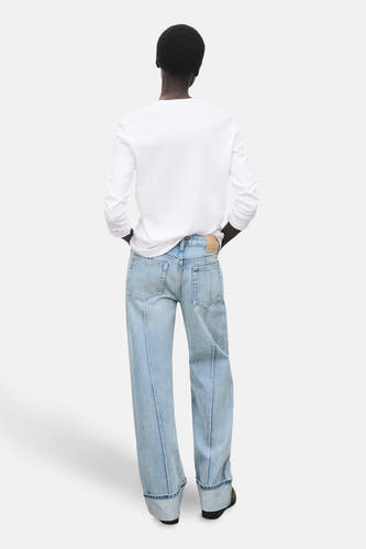 Jean droit bleu clair de MANGO, vu de derrière, avec des poches rabattues et une chemise blanche.