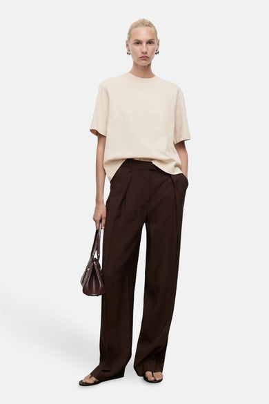 Beige T-shirt met korte mouwen van MANGO, losvallend model gecombineerd met bruine pantalon en handtas.