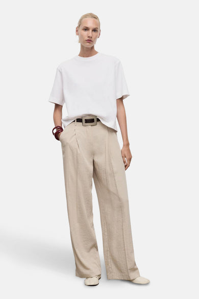 T-shirt blanc à manches courtes de MANGO, porté avec un pantalon beige et une ceinture marron.