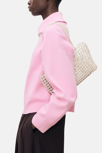 T-shirt rose à col montant de MANGO, avec un sac tressé beige et un pantalon marron.