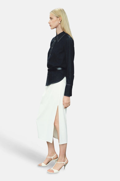 Donkerblauw denim overhemd met lange mouwen van MANGO, met een witte rok met split en witte hakken.