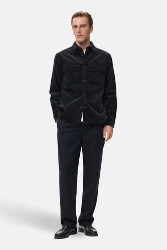 Veste courte bleue de MANGO, à manches longues et deux poches poitrine, portée sur un t-shirt blanc et un pantalon foncé.