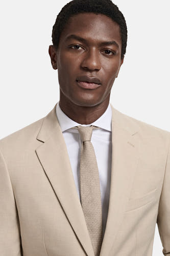 Beige blazer van MANGO, met een witte overhemd en bijpassende gestructureerde stropdas.
