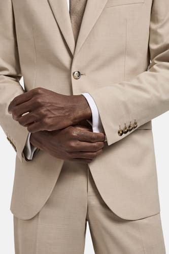 Beige blazer van MANGO, met lange mouwen en gouden knopen, als onderdeel van een tweedelig pak.
