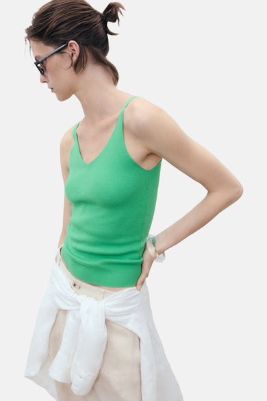 Groene singlet van MANGO, met een V-hals en een geribbelde textuur, gecombineerd met een witte blouse geknoopt om de taille.