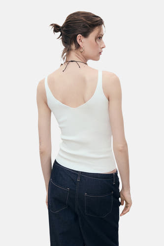 Witte singlet van MANGO, met V-hals aan de achterkant, gecombineerd met donkere jeans.