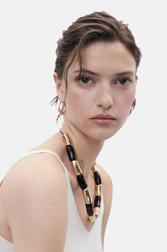 Witte singlet van MANGO, gedragen met een opvallende ketting en gouden oorbellen.
