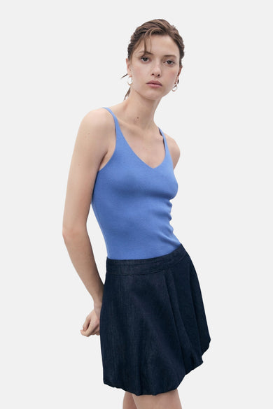 Blauwe singlet van MANGO, met dunne bandjes en ribgebreide textuur, gedragen met een donkerblauwe rok.
