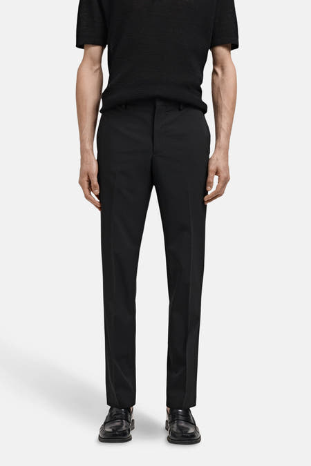 Pantalon de costume noir MANGO, avec des jambes droites et des détails de chaussures loafers.