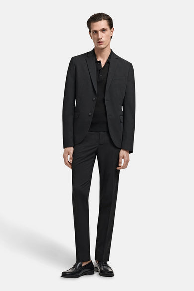 Pantalon de costume noir MANGO, combiné avec un poloshirt noir et des chaussettes noires.