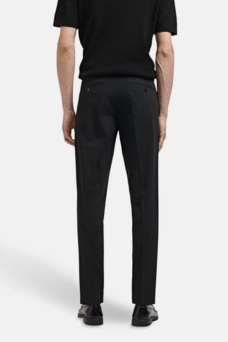 Zwarte kostuumbroek van MANGO, gezien van achteren, gecombineerd met een zwart shirt en zwarte schoenen.