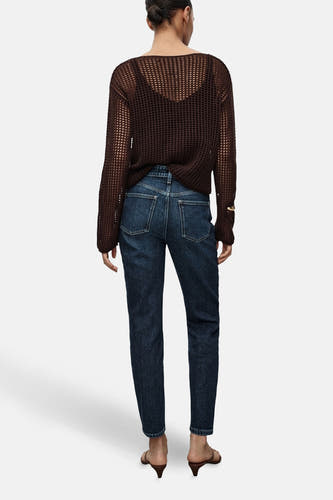 Donkerblauwe mom jeans van MANGO, gezien van achteren, gecombineerd met een bruine top en hakken.