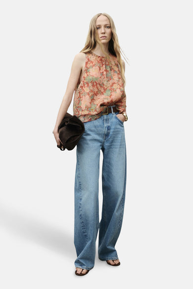 Multikleurige blouse zonder mouwen van MANGO, met bloemenpatroon en gecombineerd met wijde jeans en bruine accessoires.
