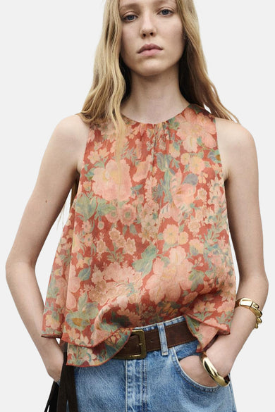 Multikleurige blouse zonder mouwen van MANGO, met bloemenprint, gedragen met een bruine riem en jeans.

