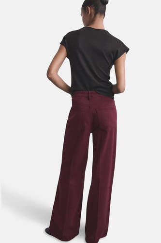 Bordeaux gekleurde jeans van MANGO, gezien van achteren met een zwarte top en opgestoken haar.