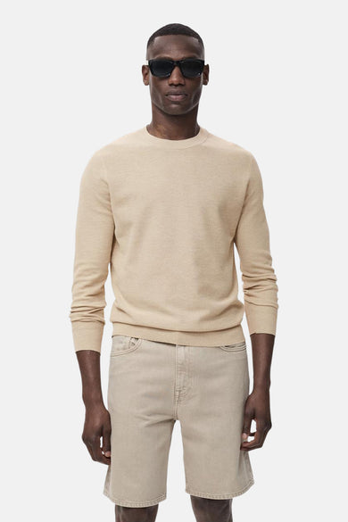 Beige trui met ronde hals van MANGO, gedragen met denim shorts en zonnebril.

