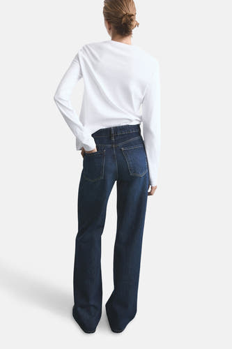 Jean bleu marine large de MANGO, avec des poches arrière et associé à un t-shirt blanc à manches longues.