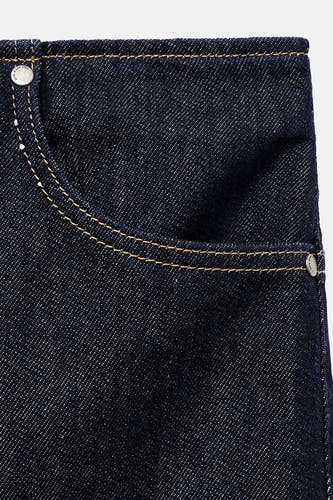Donkerblauwe denim rok van MANGO, met opgestikte zak en contrasterende stiksels, close-up.
