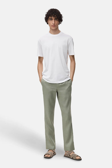 T-shirt blanc à manches courtes de MANGO, porté avec un short en lin vert et des sandales.