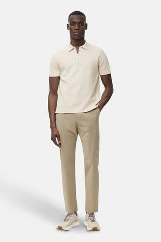 Beige broek van MANGO, gecombineerd met een lichtgekleurde polo en bijpassende sneakers.