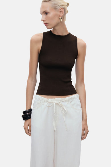 T-shirt sans manches marron de MANGO, associé à un pantalon blanc et une bande noire pour le bras.