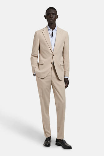 Beige kostuumbroek van MANGO, gecombineerd met een lichtblauw overhemd en zwarte schoenen.