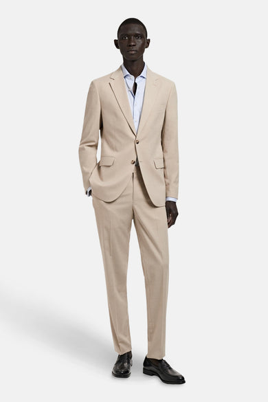 Beige kostuumbroek van MANGO, gecombineerd met een lichtblauw overhemd en zwarte schoenen.