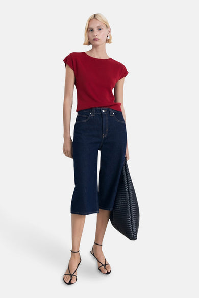 Mouwloze rode top van MANGO, gecombineerd met donkere denim culottes en zwarte sandaaltjes, plus een zwarte tas.