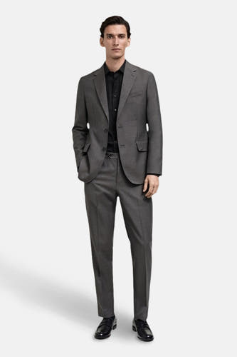 Chemise noire à manches longues de MANGO, portée sous un manteau gris.