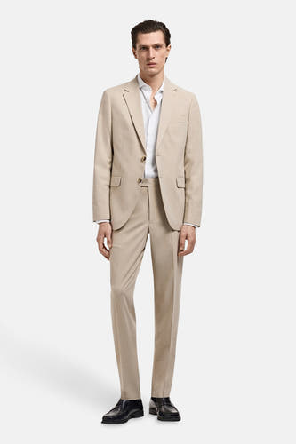 Wit overhemd met lange mouwen van MANGO, gedragen onder een beige pak en gecombineerd met zwarte schoenen.
