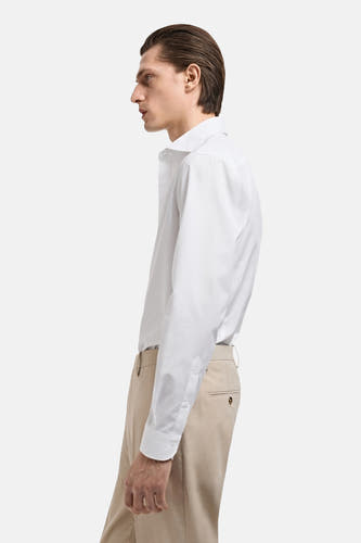 Wit overhemd met lange mouwen van MANGO, in profiel gezien met beige pantalon.