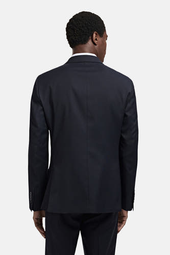 Blauwe blazer van MANGO, gezien van achteren, met subtiele taillering en knoopdetails aan de mouwen.