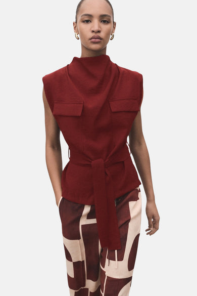 Mouwloze bordeaux blouse van MANGO, met opstaande kraag en een strikceintuur rond de taille.