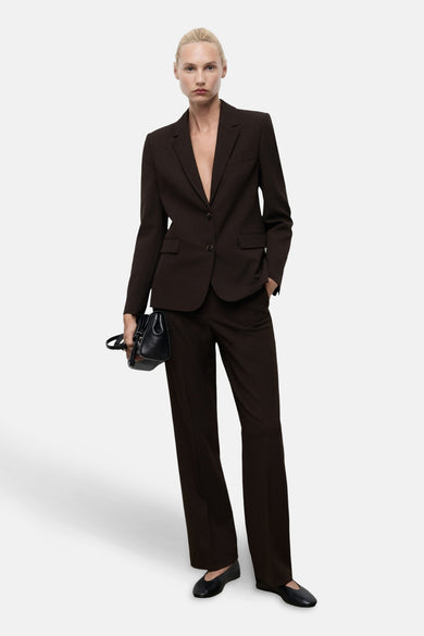 Blazer marron de MANGO, porté avec un pantalon coordonné et une poche main noire.