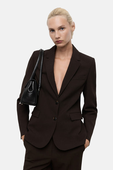 Blazer marron de MANGO, modèle cintré avec deux boutons et une poche main noire sur l'épaule.