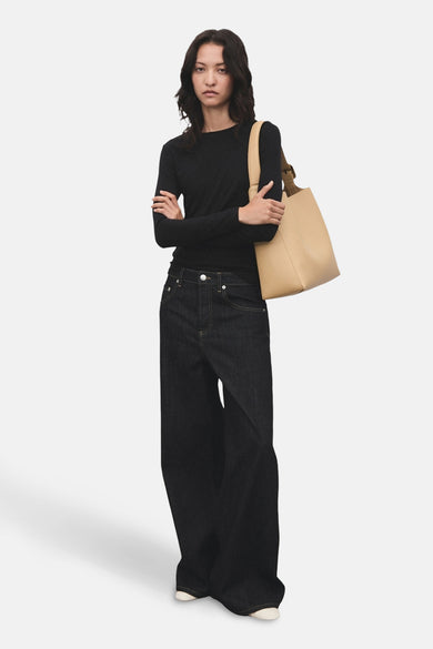T-shirt noir à manches longues de MANGO, porté avec des jeans larges et une sacoche beige.