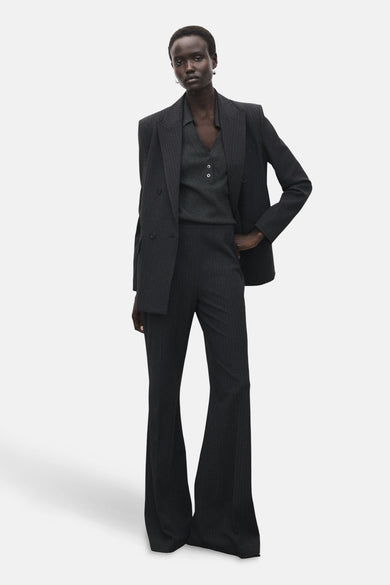 Sweat-shirt gris à col rond de MANGO, avec des détails de boutons, porté avec un pantalon rayé pour femme.