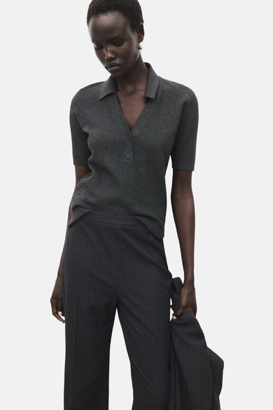 Sweat-shirt gris à col rond de MANGO, avec des manches courtes et porté avec un pantalon rayé.