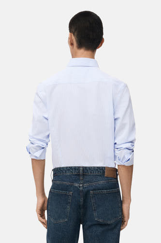 Blauw gestreept overhemd met lange mouwen van MANGO, gezien van achteren met donkerblauwe jeans.
