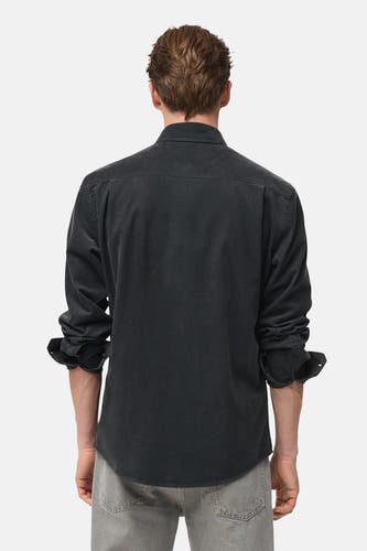 Grijs overhemd met lange mouwen van MANGO, gezien van achteren, met opgerolde mouwen en grijze jeans.
