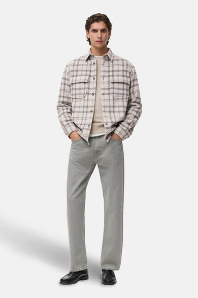 Korte multicolor jas van MANGO, met een ruitpatroon en twee borstzakken, gedragen over een beige trui en grijze jeans.
