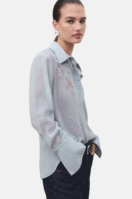 Blauw overhemd met lange mouwen van MANGO, met broderie details aan de voorkant en gedragen met jeans.