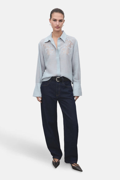 Blauw hemd met lange mouwen van MANGO, met bloemenborduursel en gedragen met donkere jeans en zwarte riem.