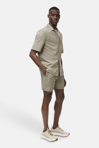 T-shirt kaki avec manches courtes de MANGO, porté avec des shorts coordonnés et des baskets beige.