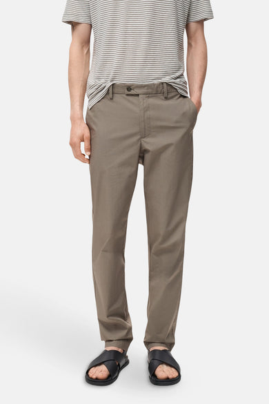 Bruine broek van MANGO, gecombineerd met een gestreept shirt en zwarte sandalen.