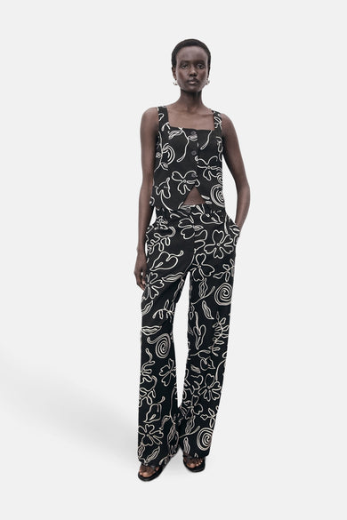 Zwarte blouse zonder mouwen van MANGO met een wit bloemenpatroon, gecombineerd met een bijpassende broek.