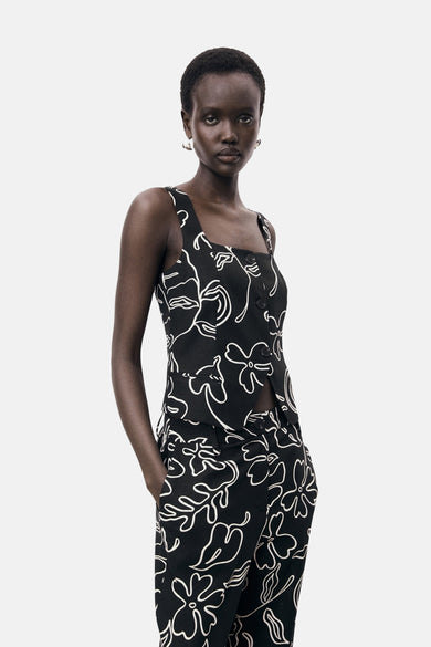 Zwarte mouwloze blouse van MANGO, met witte bloemenprint en knoopsluiting.